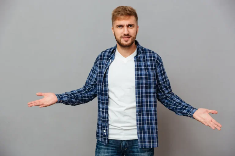 portrait of a bearded casual man shrugging shoulders isolated on a gray background